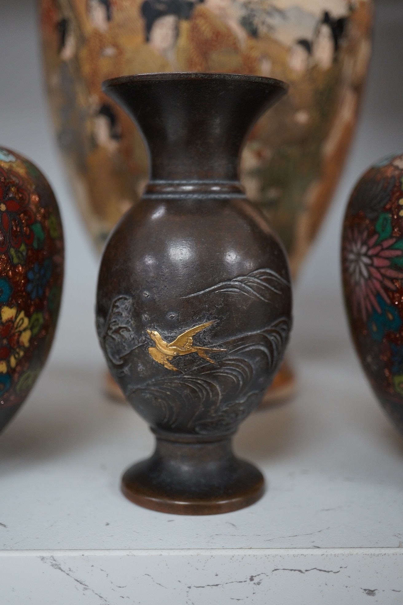 A pair of Japanese cloisonné enamel jars and covers, a Japanese bronze and gold overlaid small vase and a Satsuma pottery vase, tallest 22cm high (4). Condition - finial loose and one missing on cloisonné jars and covers